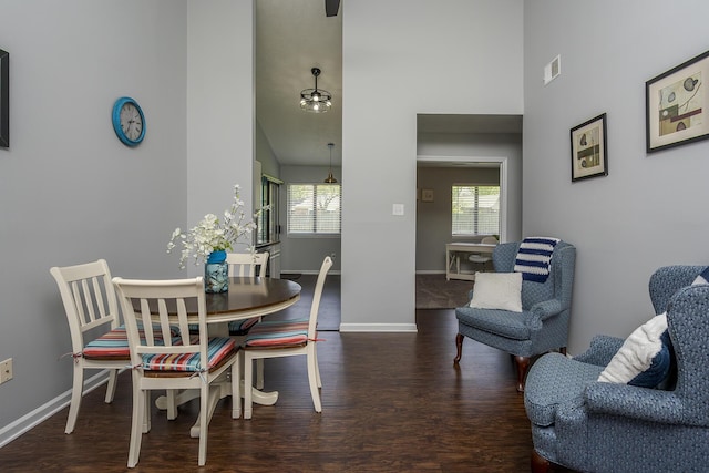 dining room featuring a towering ceiling, visible vents, wood finished floors, and baseboards