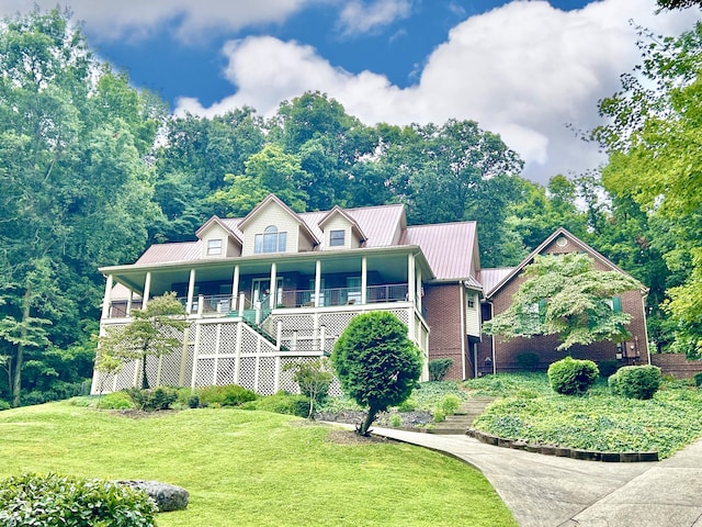 view of front of home with stairway, metal roof, a porch, and a front lawn
