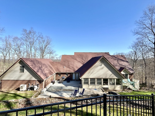 rear view of property with a fenced backyard, brick siding, a sunroom, a patio area, and a pool