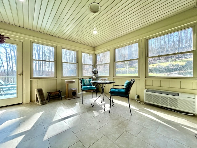sunroom / solarium with a wall mounted air conditioner, tile patterned flooring, and plenty of natural light