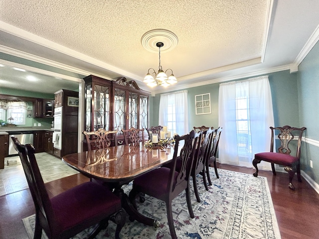 dining area with a chandelier, baseboards, a raised ceiling, a textured ceiling, and crown molding