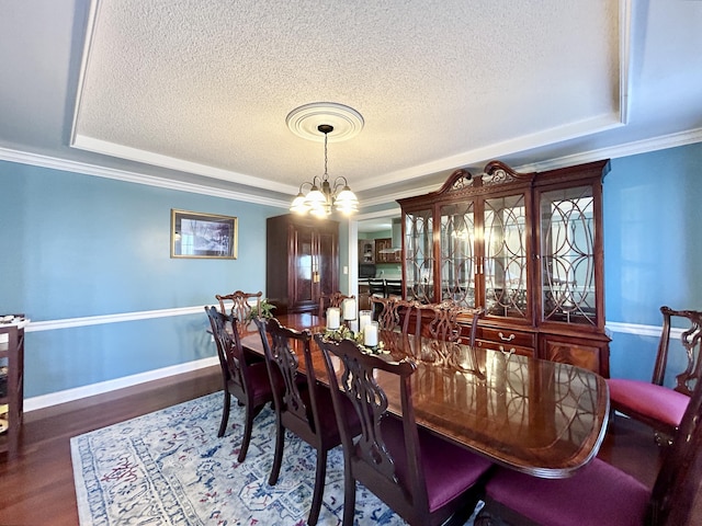 dining room with a raised ceiling, a textured ceiling, and wood finished floors
