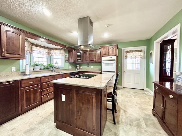 kitchen featuring a kitchen bar, black electric cooktop, white double oven, a kitchen island, and island range hood