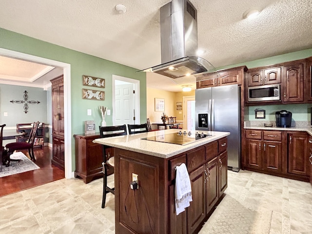 kitchen featuring island exhaust hood, a center island, a breakfast bar area, a textured ceiling, and appliances with stainless steel finishes