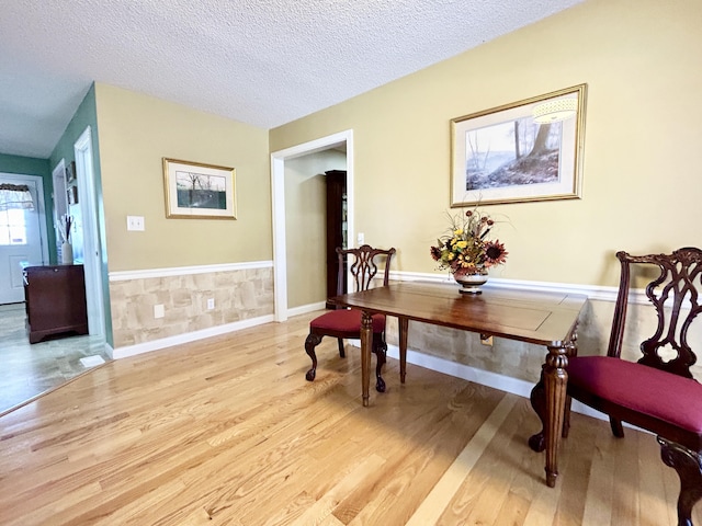 sitting room with a textured ceiling, wood finished floors, and a wainscoted wall