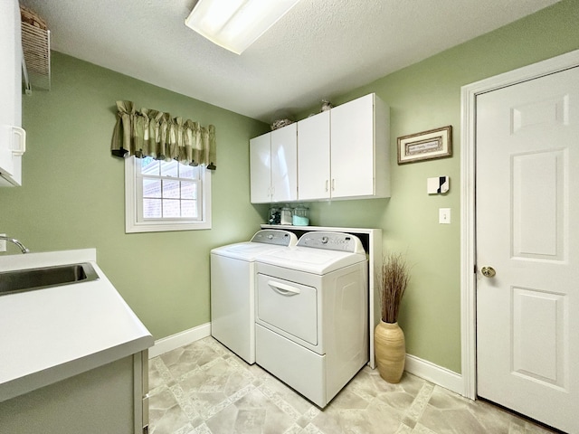 clothes washing area with a sink, separate washer and dryer, cabinet space, and baseboards