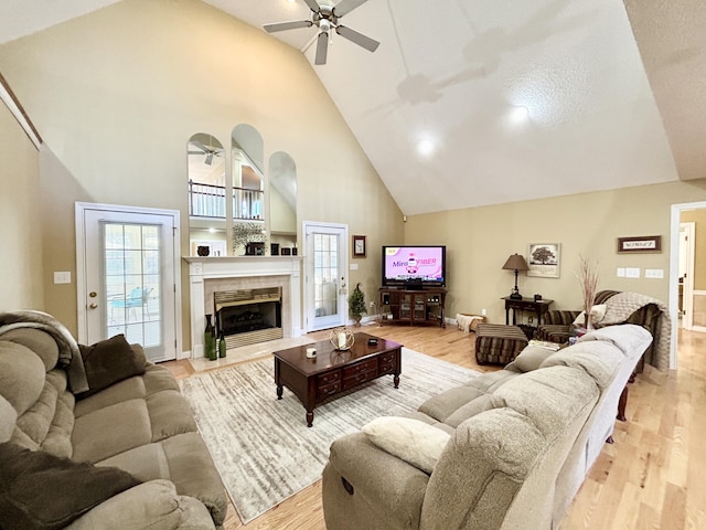 living room with light wood-style flooring, ceiling fan, a healthy amount of sunlight, and high vaulted ceiling