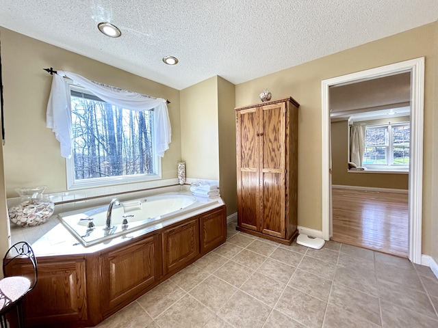full bath with baseboards, a textured ceiling, tile patterned flooring, and a bath