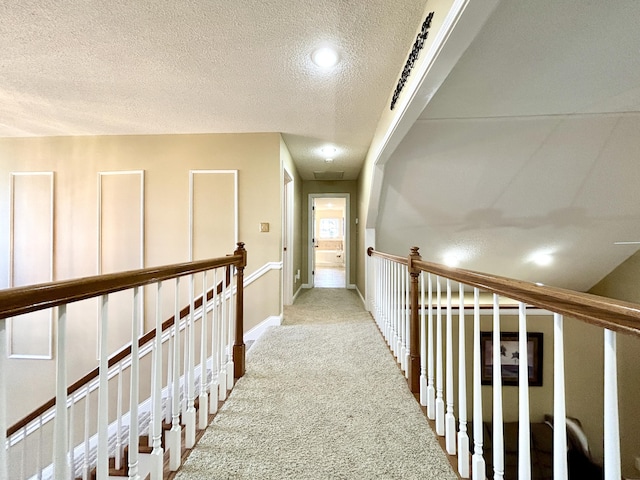 hall featuring a textured ceiling and light colored carpet