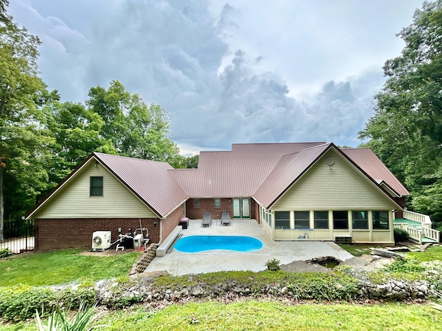 rear view of house with metal roof, a patio, an outdoor pool, and brick siding