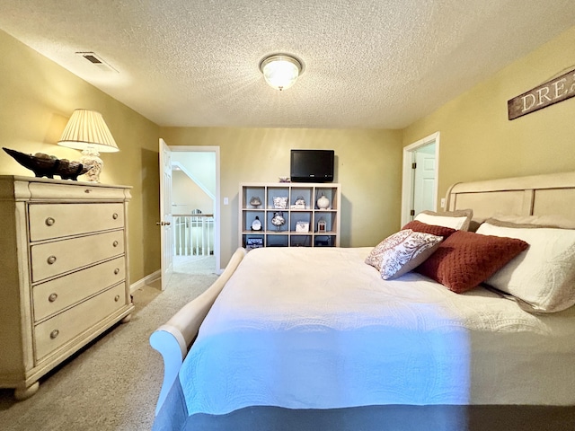 carpeted bedroom featuring a textured ceiling and visible vents