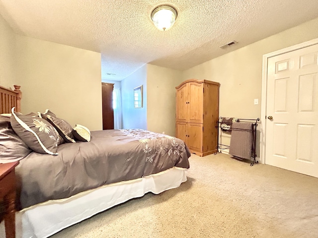bedroom featuring a textured ceiling, visible vents, and light carpet