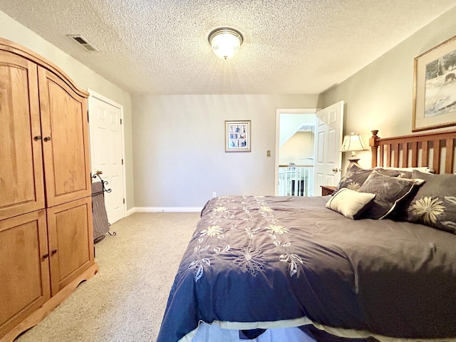 bedroom featuring a textured ceiling, visible vents, light colored carpet, and baseboards