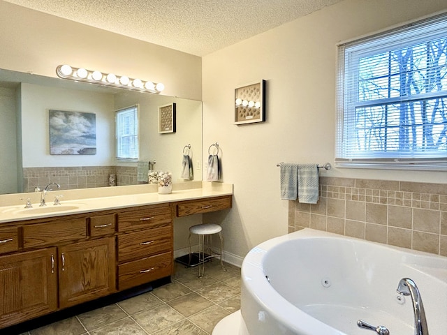 full bath featuring a textured ceiling, tile patterned flooring, vanity, and a jetted tub