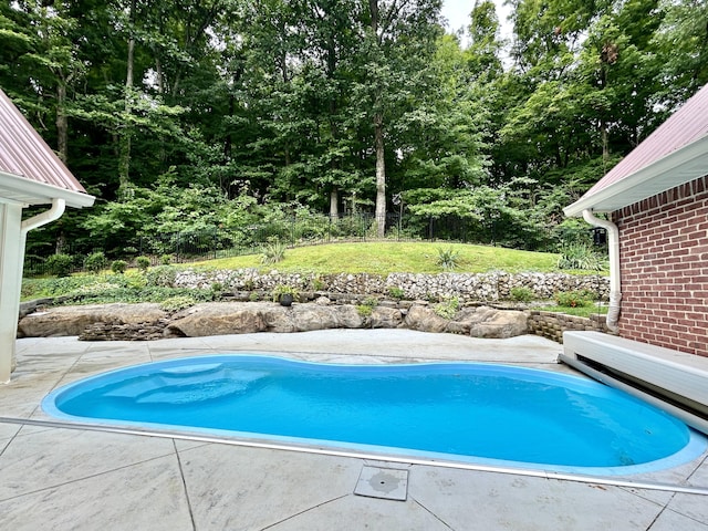 view of swimming pool with a lawn, fence, and a patio area
