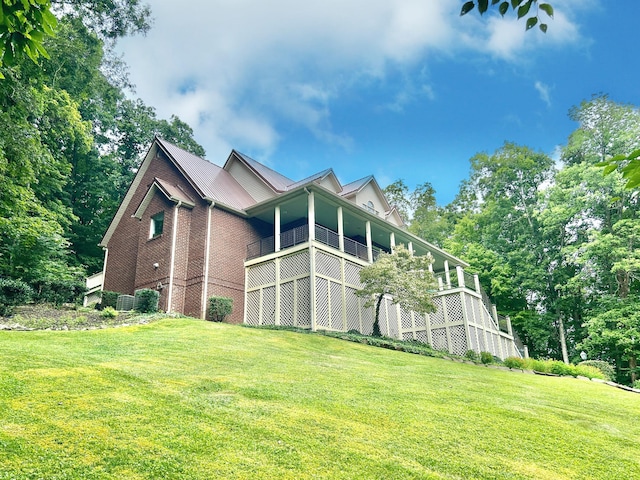 view of side of property with a lawn, central AC, and brick siding