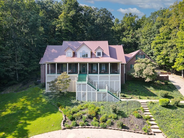 view of front of house with stairway, metal roof, a front lawn, and a sunroom