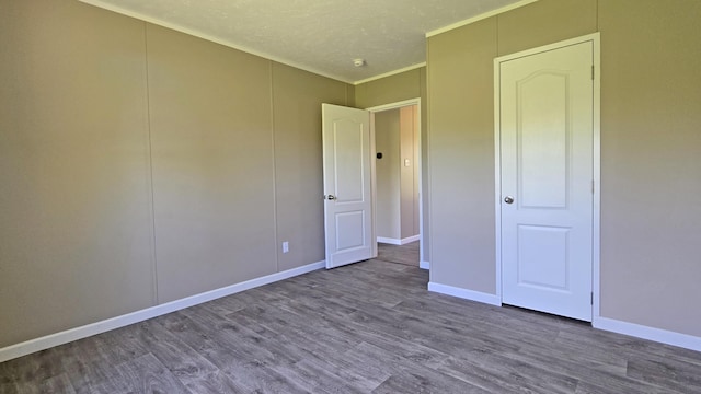 unfurnished bedroom with ornamental molding, wood finished floors, and baseboards