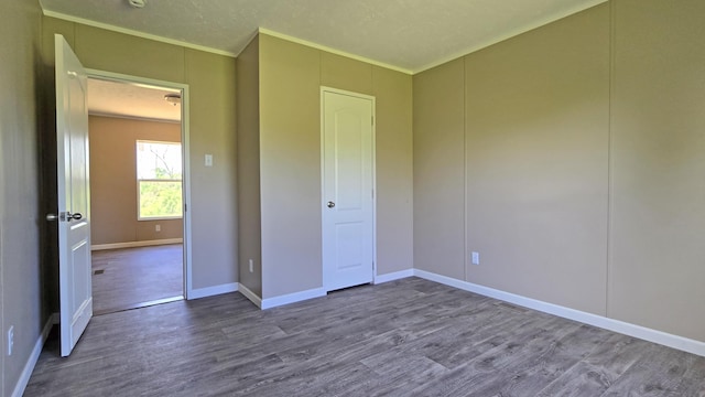 unfurnished bedroom featuring crown molding, wood finished floors, and baseboards