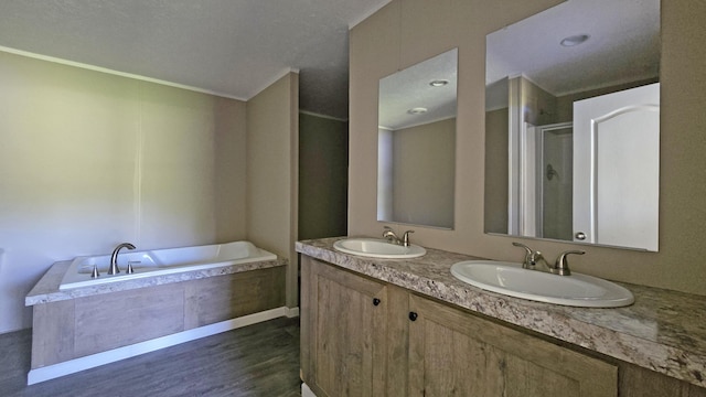 bathroom featuring wood finished floors, a shower stall, a garden tub, and a sink