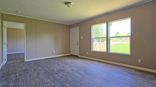unfurnished room with dark wood-style flooring, a healthy amount of sunlight, and baseboards