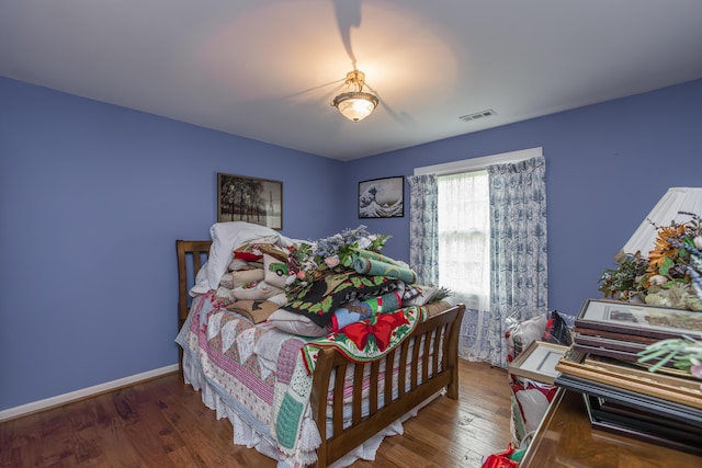bedroom featuring baseboards, wood finished floors, and visible vents