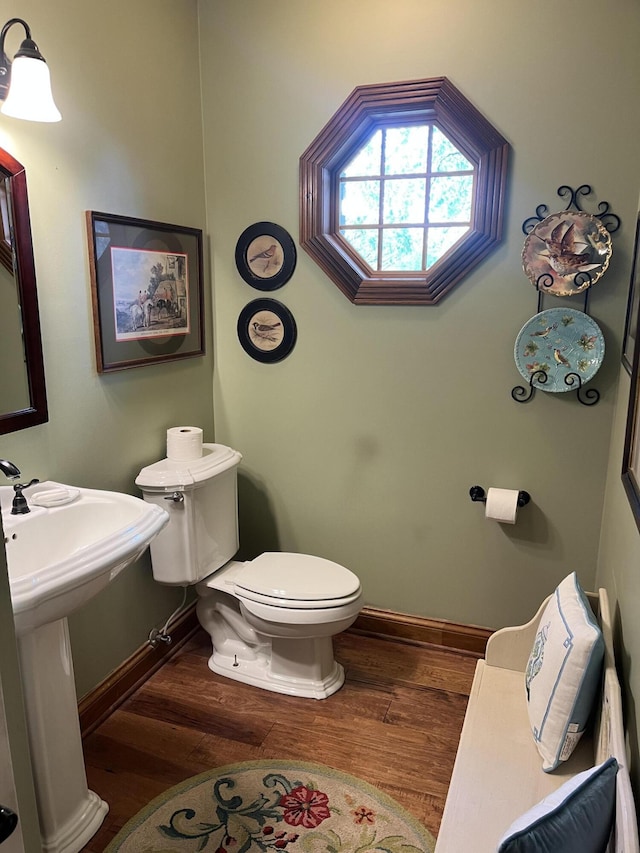bathroom with toilet, baseboards, a sink, and wood finished floors