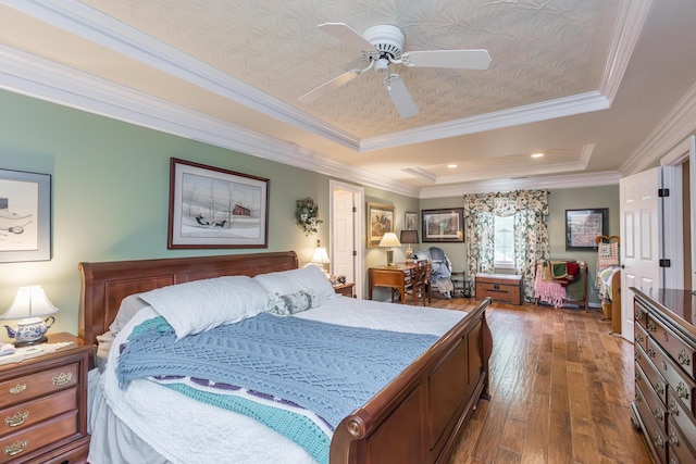bedroom featuring ornamental molding, wood-type flooring, a tray ceiling, and ceiling fan