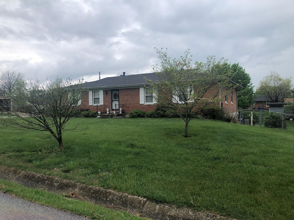 view of front facade with fence, a front lawn, and brick siding