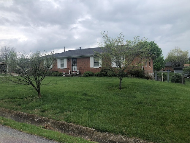 view of front facade with fence, a front lawn, and brick siding