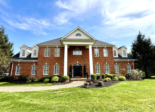 greek revival inspired property with a front yard and brick siding