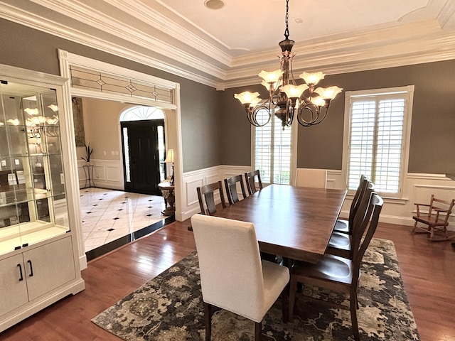 dining space with dark wood finished floors, wainscoting, ornamental molding, and a notable chandelier