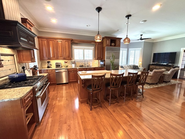 kitchen with a sink, decorative backsplash, light wood-style floors, a kitchen breakfast bar, and high end appliances