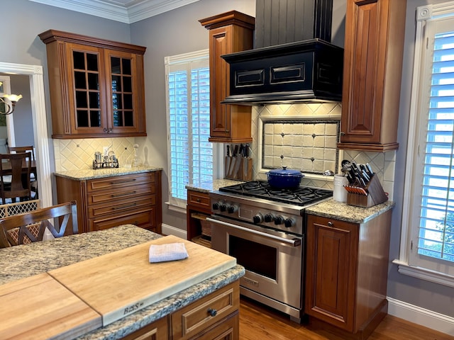 kitchen featuring decorative backsplash, glass insert cabinets, high end range, ornamental molding, and custom exhaust hood