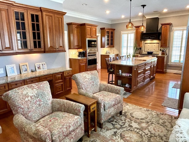 kitchen with brown cabinets, open shelves, premium range hood, a center island, and light wood finished floors