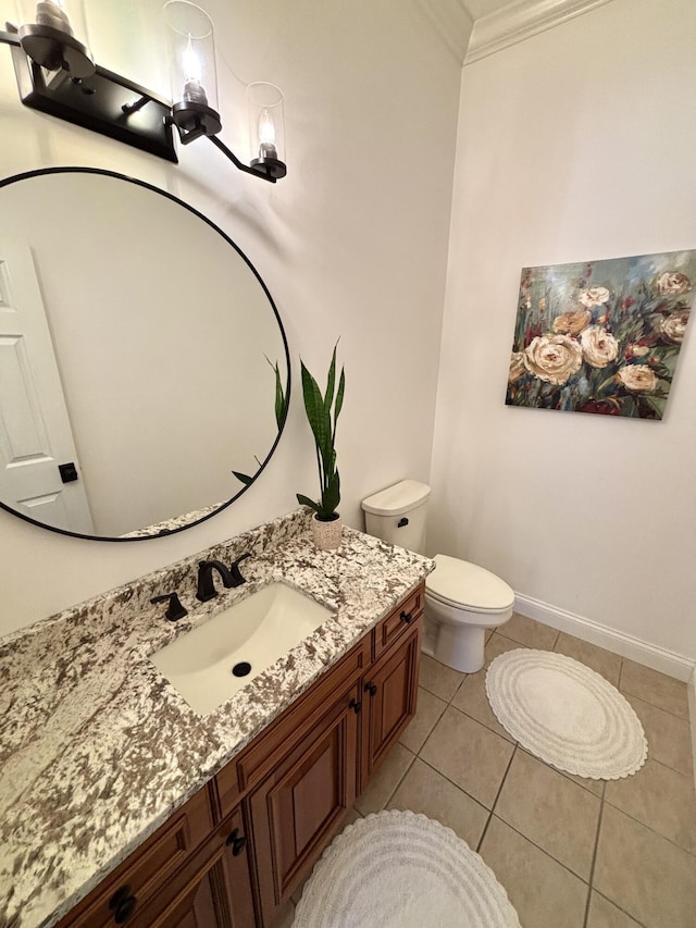 half bathroom with vanity, tile patterned floors, toilet, baseboards, and ornamental molding