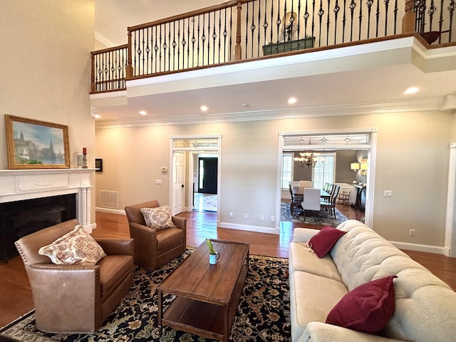 living room with baseboards, visible vents, ornamental molding, and a high ceiling