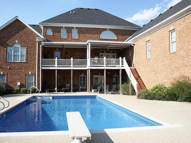 rear view of house featuring brick siding, an outdoor pool, stairway, and a patio area