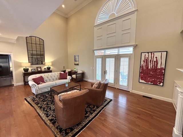 living room with crown molding, a high ceiling, wood finished floors, and baseboards