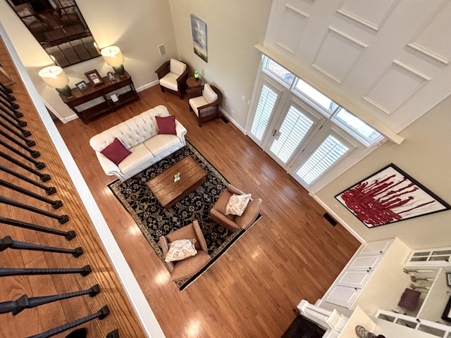 living area with a towering ceiling, wood finished floors, and baseboards