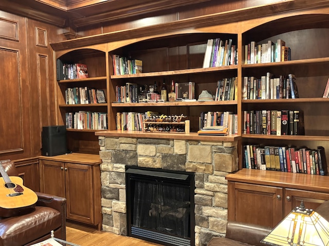 living area featuring a fireplace, light wood-style floors, and crown molding