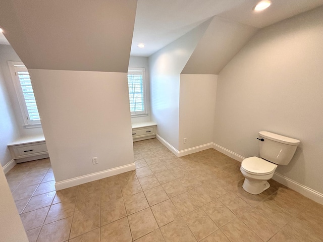 bathroom featuring toilet, tile patterned flooring, vaulted ceiling, and a wealth of natural light