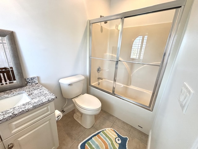 bathroom with tile patterned flooring, toilet, vanity, baseboards, and bath / shower combo with glass door