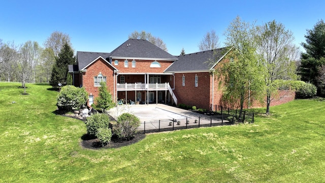 rear view of house with a lawn, fence, stairway, and brick siding