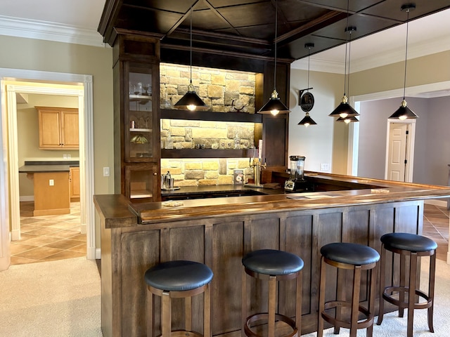 bar with light tile patterned floors, pendant lighting, light colored carpet, ornamental molding, and indoor wet bar