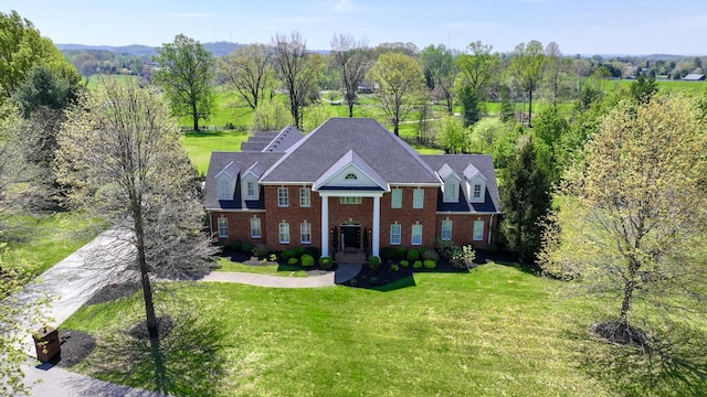 greek revival inspired property featuring a front yard and brick siding