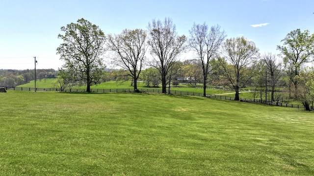 view of yard with fence and a rural view