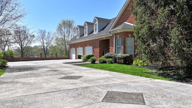 view of side of home with driveway and brick siding