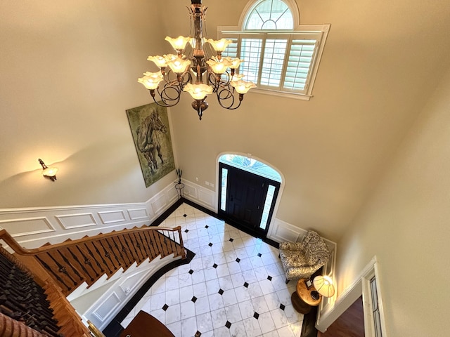 entrance foyer with an inviting chandelier, tile patterned floors, and baseboards