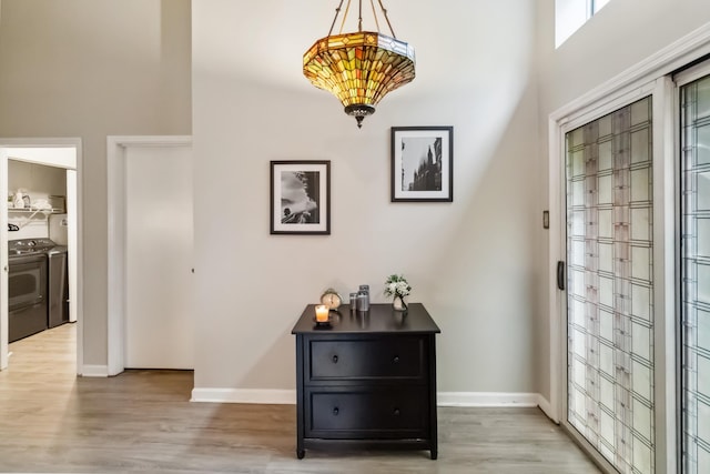 entrance foyer featuring washer and dryer, light wood-style flooring, and baseboards